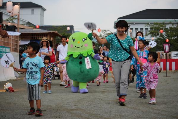 篠山市のマスコット人形まめりんが、祭りの会場でみんなと一緒に歩いている写真