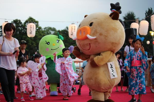 篠山市のマスコット人形まるいの・まめりんが赤いカーペットの上を浴衣姿の子供達と歩いている写真