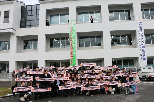 ろうあ者の皆さんが、文字の入ったピンクのタオルを両手で広げ集合写真