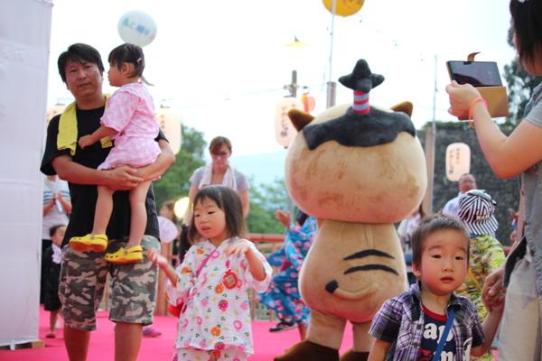 家族連れの中に篠山市のマスコット人形「まるいの」が後ろを向いていている写真