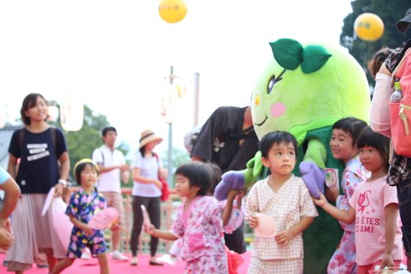 マスコット人形のまめりんが子供達と手を繋いで歩いている写真