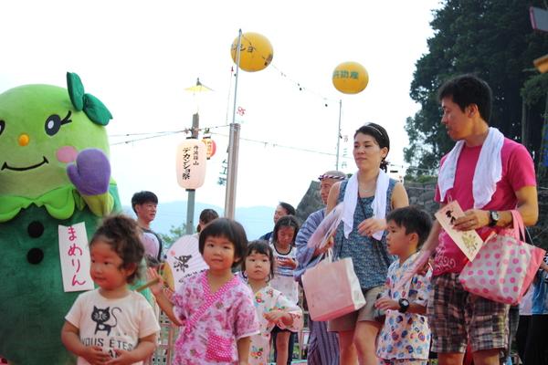 マスコット人形のまめりんが仁平さんを着た女の子たちと一緒に歩いている写真