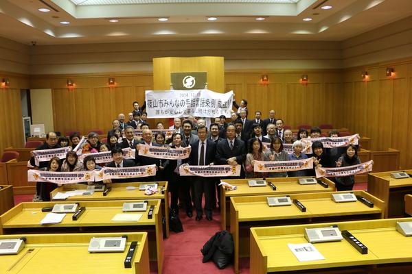 篠山市みんなの手話言語条例の垂れ幕の手前に、ろうあ関係の皆さんで集合写真