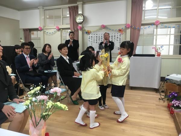 在園生の3名から花を受け取る卒園生の松宮朱利さんの写真