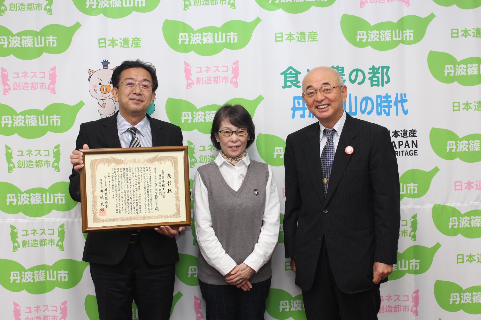 表彰状を持った国際理解センター職員と市長の記念撮影