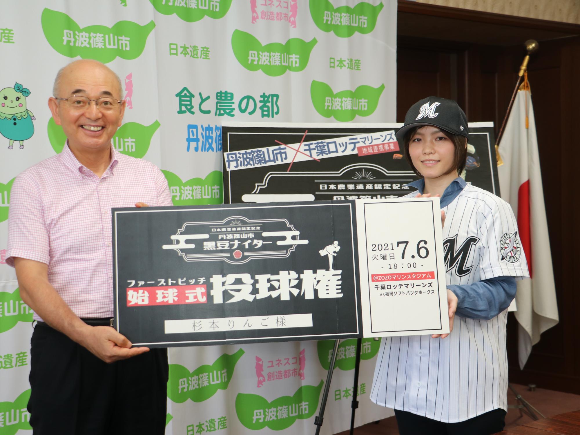 千葉ロッテマリーンズの帽子とユニフォームを着た女性と市長が、大きな始球式投球権というパネルを持っている