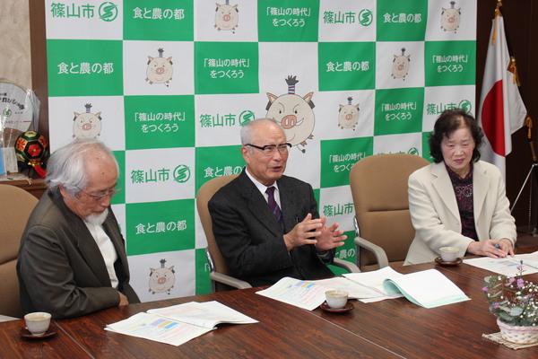 中央の新家 龍会長が話されて、左に小森 星児副会長、右に園田 美子委員が座っている写真