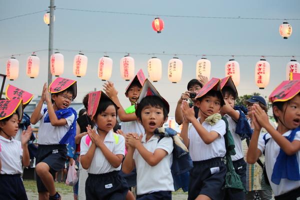 子供達が両手を顔の横におき、踊っている写真