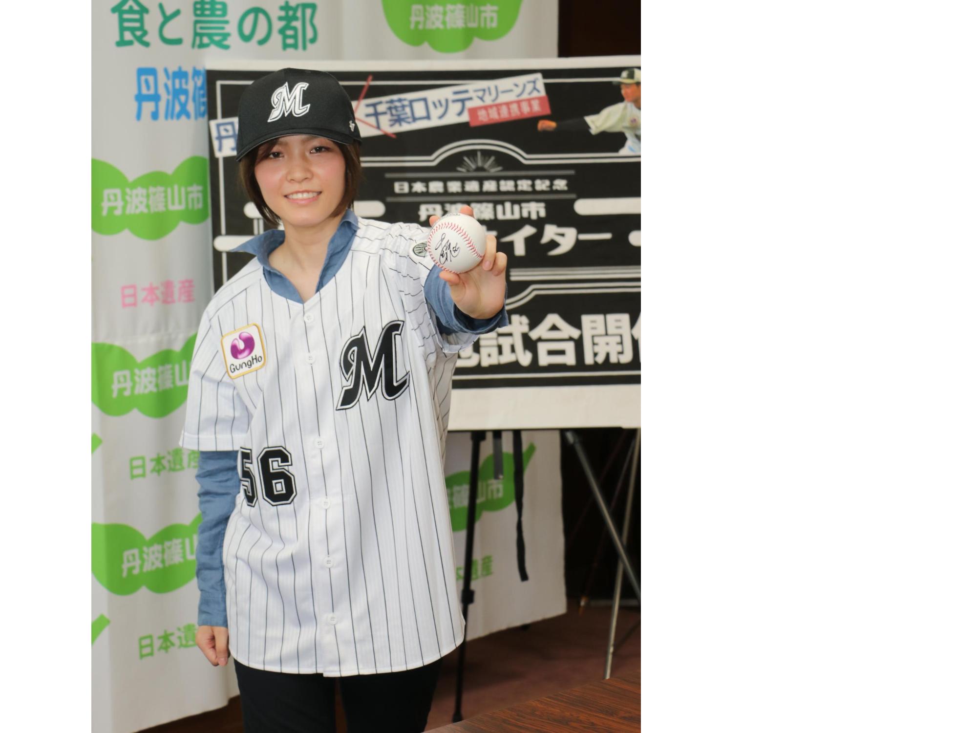 千葉ロッテマリーンズの帽子とユニフォームを着た女性が、サインボールを左手に持っている