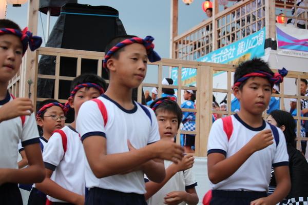 体操服を着てねじり鉢巻きをした男の子たちが踊っている写真