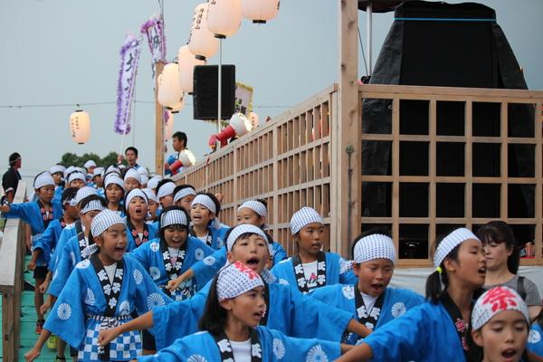 お祭りの法被を着た子供達が声を出しながら踊っている写真