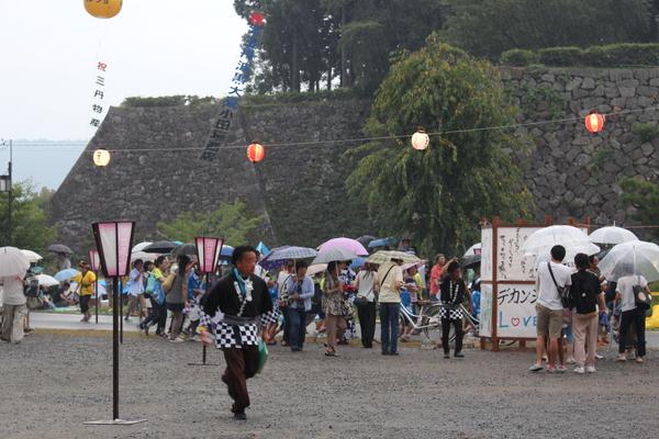 お祭りの会場で雨が降りみんな傘をさしている写真
