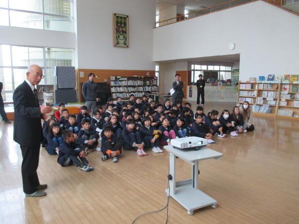 床に30名ほどの子どもたちが座っていて、市長が左側に立っている写真