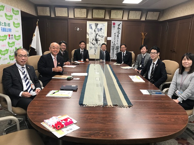 応接室で椅子に座って市長、副市長、出向職員と所属部署の職員などの記念撮影