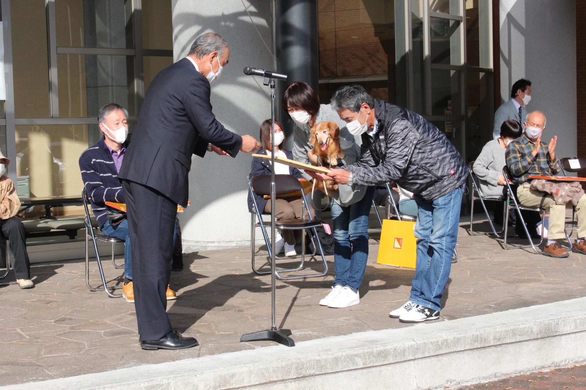 飼い犬を抱いて表彰を受ける飼い主