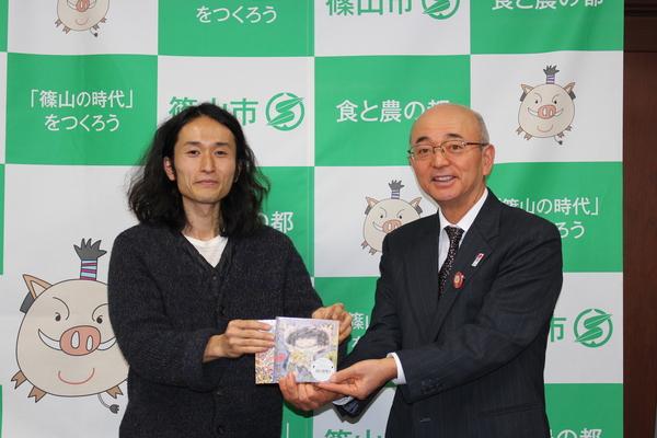 市長が高木さんからCD（絵本つき）を頂き二人でCDに手をそえている写真