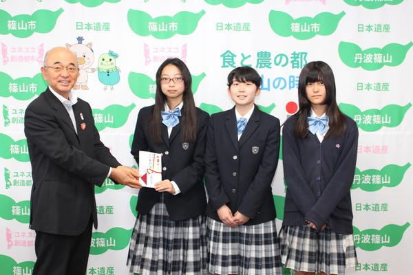 市長が代表の女子生徒と目録を持っている写真