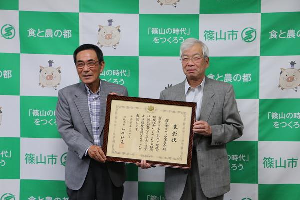 額縁に入った表彰状を2人で持って笑顔で写っている谷口会長と檜皮さんの写真