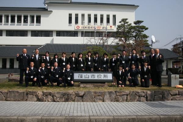 篠山市役所の前に2列に整列し、ガッツポーズをする新規職員20名と関係者の集合写真