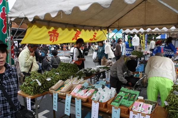 テントの中にお茶や豆などの商品が並べられており、商品を見ているお客様の写真