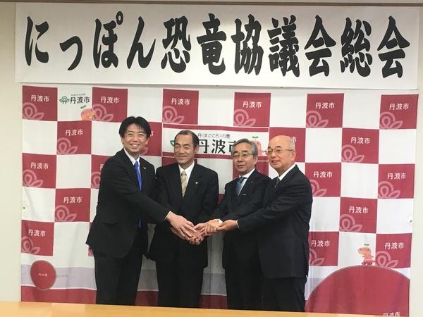 にっぽん恐竜協議会の参加者3名と市長が手と手を取り合って記念撮影