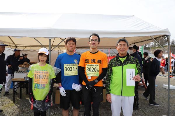 3名の男性と帽子を被った女性がテント前で写っている写真