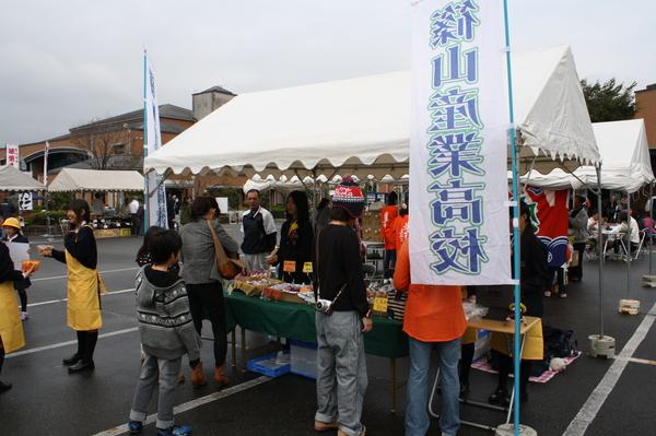 白いテントの横に篠山産業高校ののぼり旗があり、お客様がテント内にある商品を見たり、商品の案内をしている生徒の写真