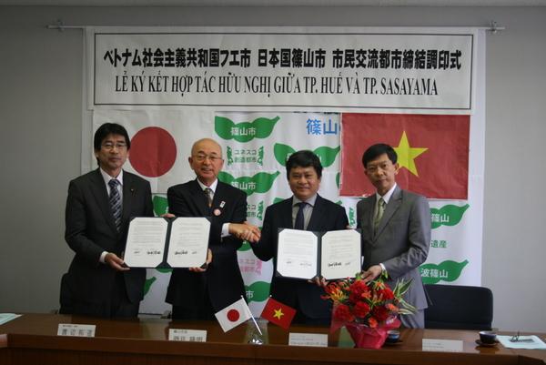 市長とスーツ姿の男性3人が並んでいて、握手をしながら調印書を見せている写真