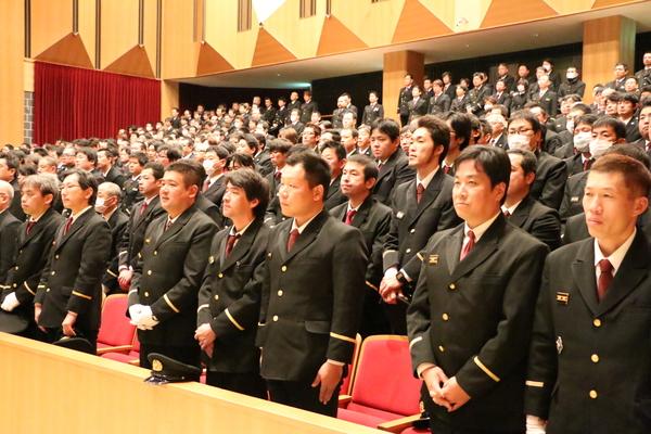 出初式にて客席に立っている制服姿の男性らの写真