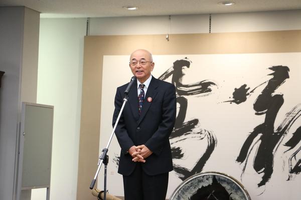 スーツ姿の市長がスタンドマイクで挨拶をしている写真