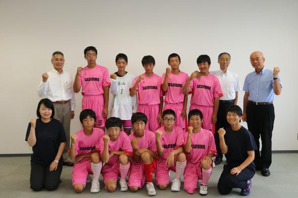 ピンクのユニフォーム姿の中学校ホッケー部と市長でガッツポーズ写真