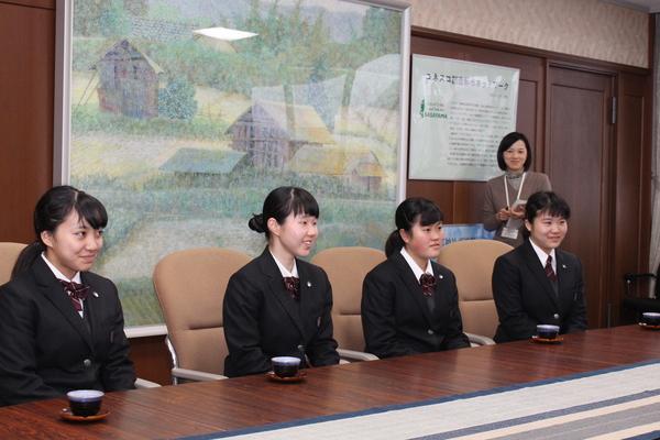 微笑んだ、制服姿の4名の女子生徒が、座っている写真