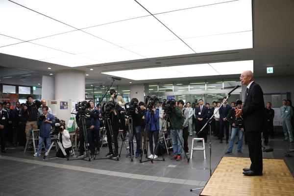 沢山の報道陣の前で、市長がスタンドマイクで挨拶をしている写真