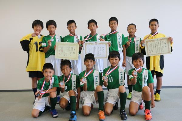 12名の部員たちが首にかけたメダルを見せるように手で持って並んでいる集合写真