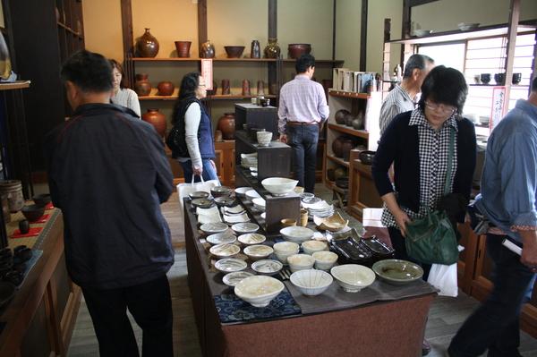 店内に並べられた、たくさんの陶器を見ている人々の写真