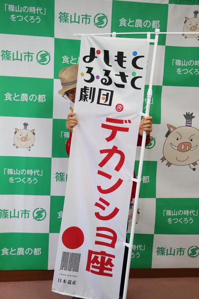 よしもとふるさと劇団デカンショ座ののぼり旗を持ちのぼり旗から少しだけ顔を出している市長の写真