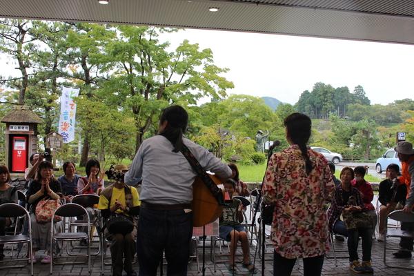 10名ほどの座っている人の前でギターを持った男女が演奏している写真