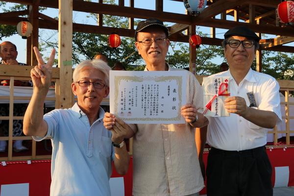 笑顔で表彰状と、賞金をもつ男性3名の写真