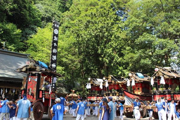 5台の山車を青い法被を着た男性達が運んでいる写真