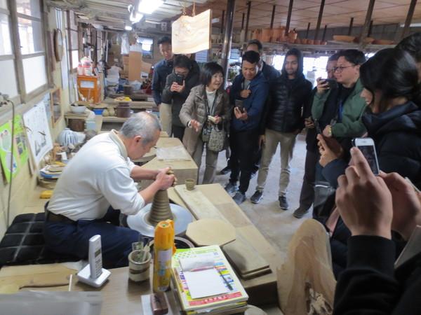 ブータンの若手行政官13人が焼き物のろくろの工程を写真を撮りながら見学している写真