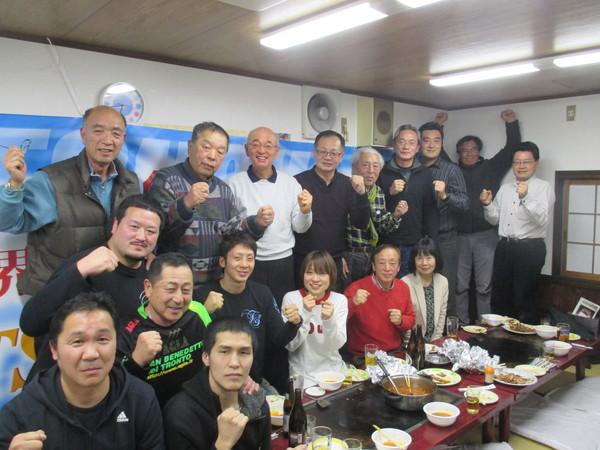 お好み焼き屋さんで、みんなで拳を前にポーズをとっている集合写真