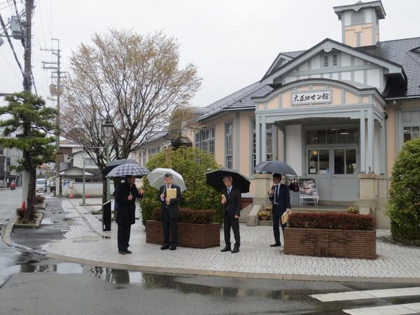 大正ロマン館の前で視察に来られている伊丹副局長さんと関係者の皆さんが傘をさして写っている写真