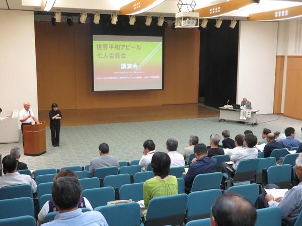 プロジェクトスクリーンの斜め横で、マイクをもって話す市長とその横で手話をする女性の写真