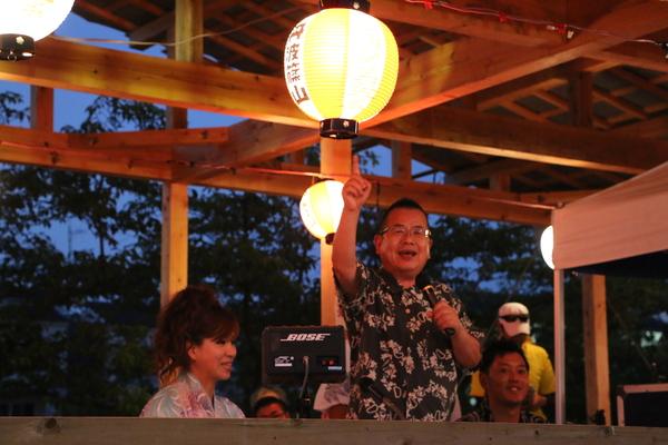 ふるさと応援団長の桂 文珍さんが人差し指を上げてマイクを持っている写真