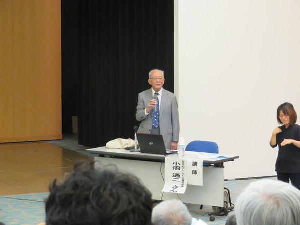 マイクを持て話す、講師の小沼 通二さんの写真