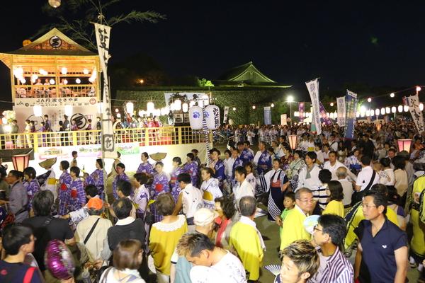 ライトアップされたやぐらの周りにあつまる沢山の人々の写真