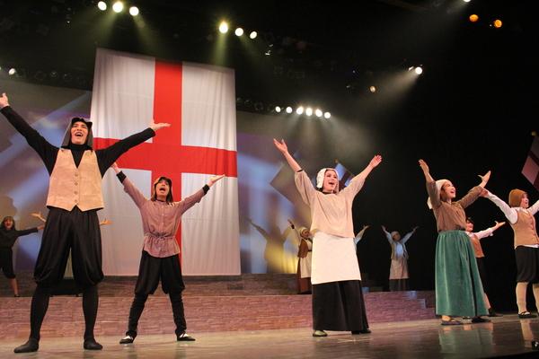 様々な衣装を着て両手を上にあげた動きをしている出演者の写真