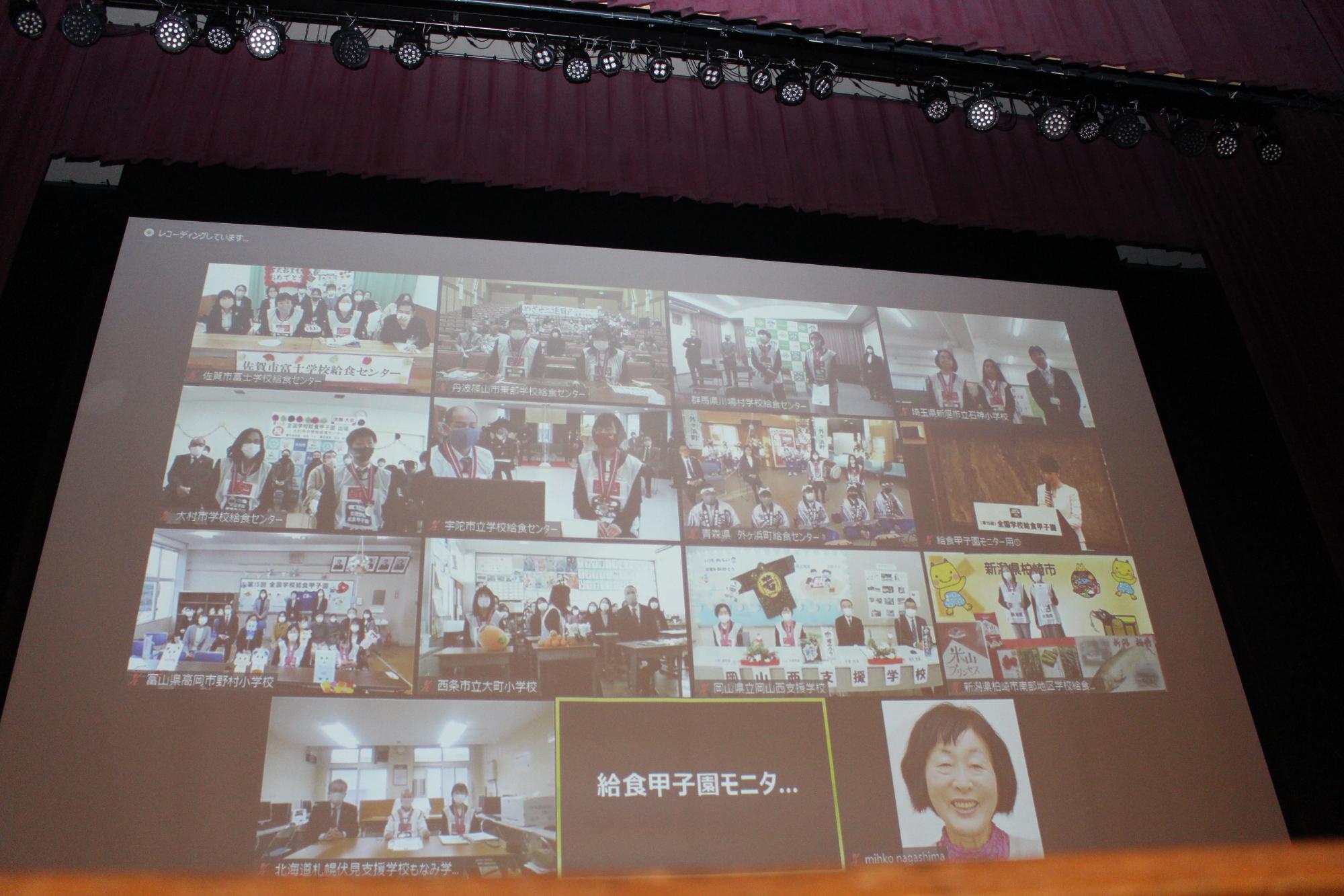 スクリーンに、各代表チームの映像が映し出されている