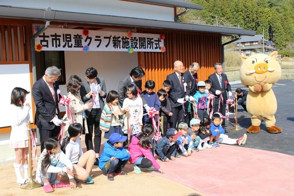 古市児童クラブ新施設開所式で子供たちとまるいの、関係者らが児童クラブの前で横2列に並んでいる写真