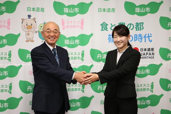 中西 美加さんと市長が両手で握手をし、カメラ目線で写っているツーショット写真